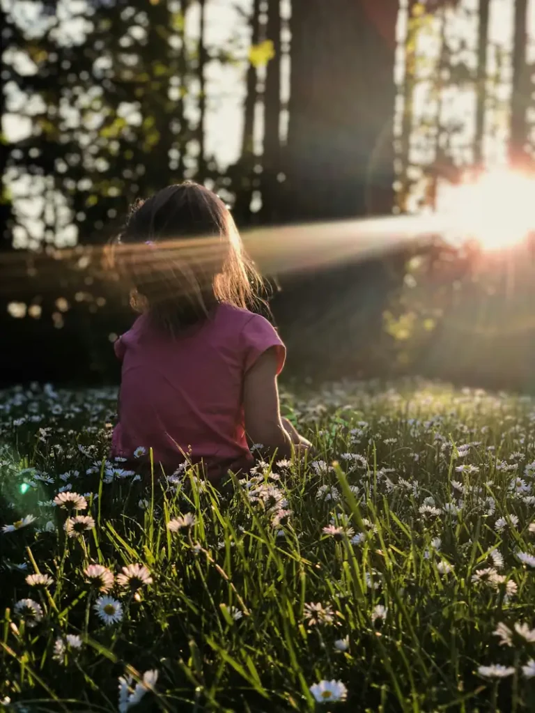 Decorative girl sitting on field facing sun